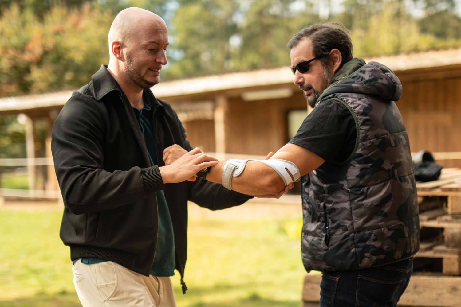 Man helpt bij het aanbrengen van de Masalo Cuff MED tegen tenniselleboog, golferselleboog, muiselleboog